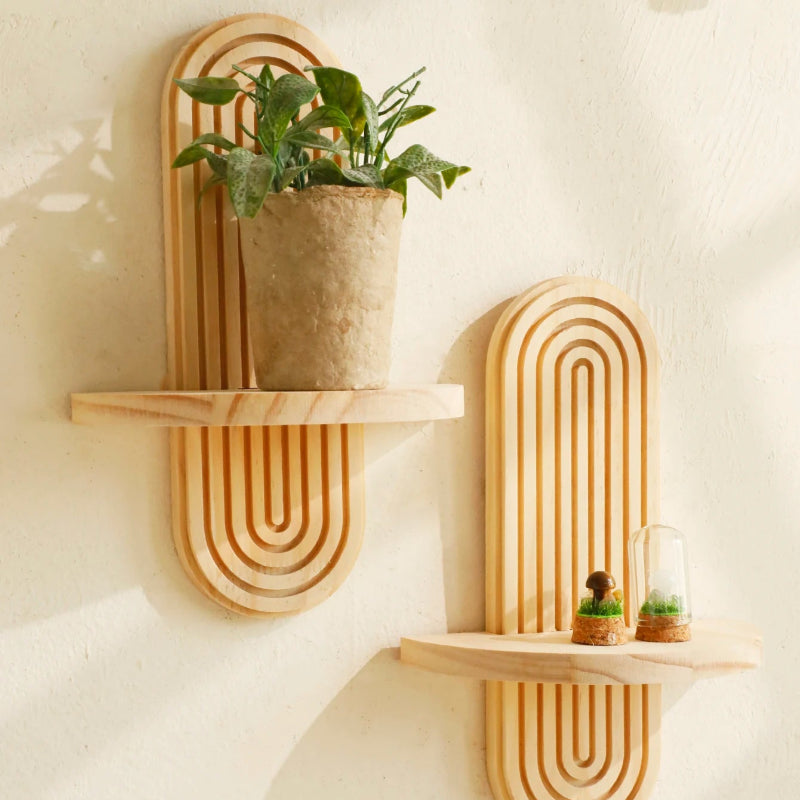 Double-tier wall shelf in geometric wood design holding plants and ornaments.