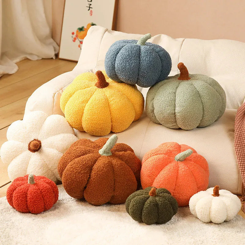 An assortment of soft, pumpkin-shaped pillows in various colors and sizes are arranged on a white sofa and rug.