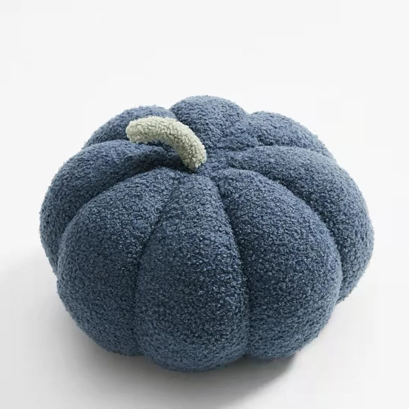 A fluffy, dark blue pumpkin-shaped pillow with a light green stem.