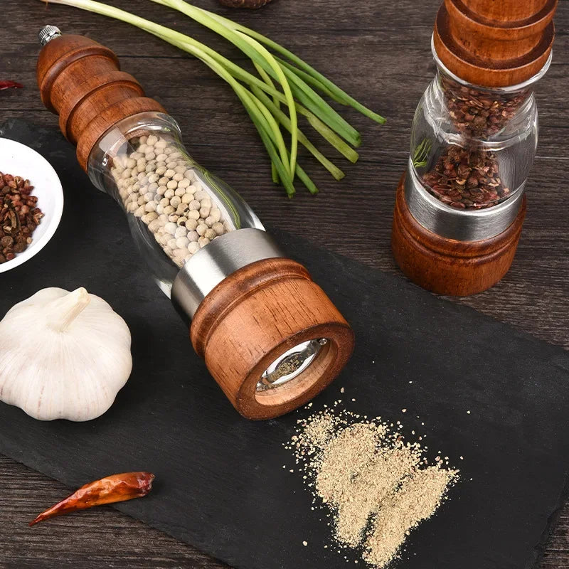 Wooden pepper mills with spices on a dark surface