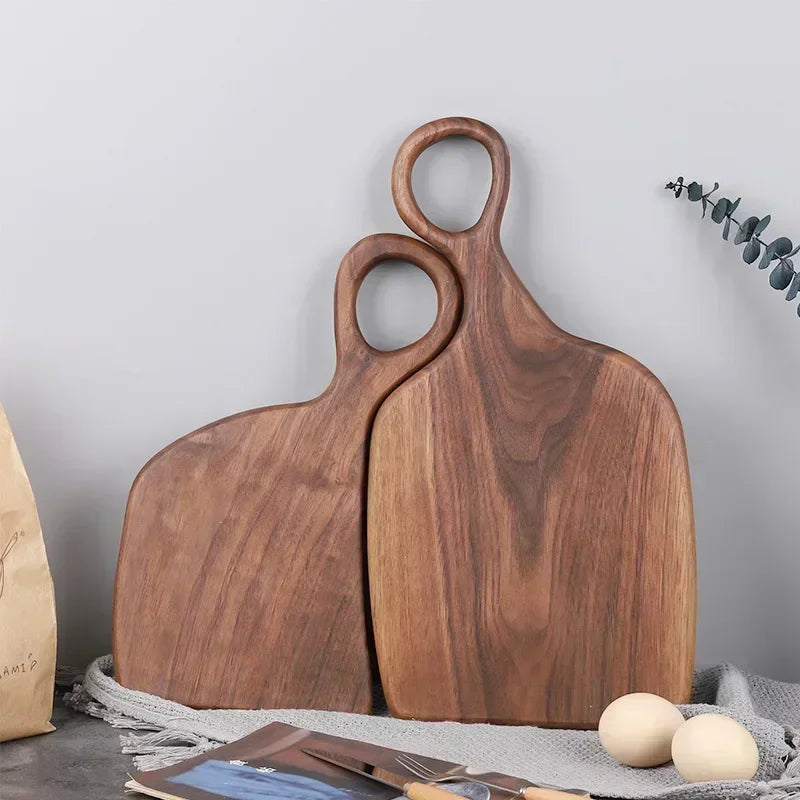 Two wooden cutting boards with handle cutouts lean against a gray surface.