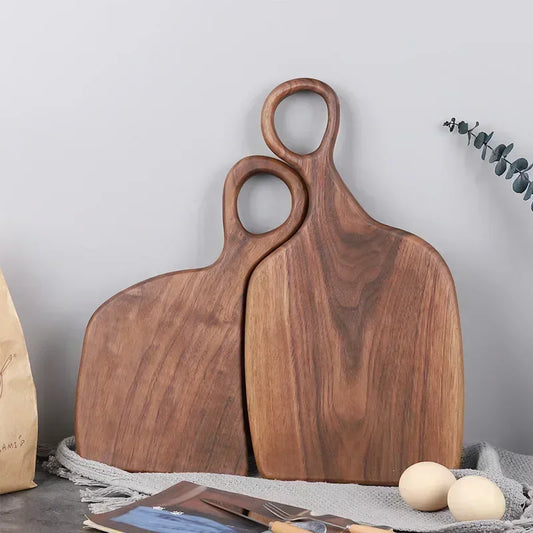 Two wooden cutting boards with handle cutouts lean against a gray surface.
