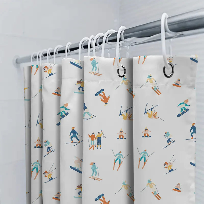 Close-up of a white shower curtain hung on a rod with a pattern of cartoon skiers and snowboarders in blue, orange, and teal.