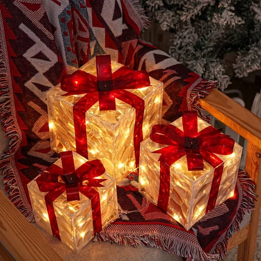 Three glowing gift boxes with red bows on a patterned throw blanket.