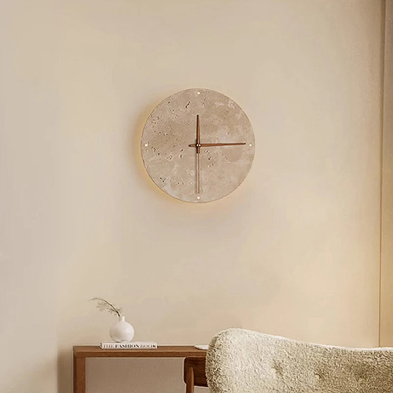 A round wall clock with a light-colored, textured face and simple red hands is mounted on a light beige wall.
