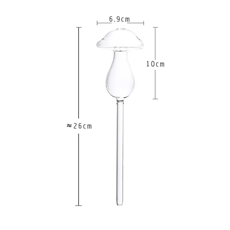 A clear glass, mushroom-shaped plant waterer is displayed with approximate measurements: the mushroom cap is about 6.9 cm wide, the body is about 10 cm long, and the total length of the waterer, including the spike, is approximately 26 cm. This is a Lomodo Plant Waterer Transparent Glass Self Watering Bulb.