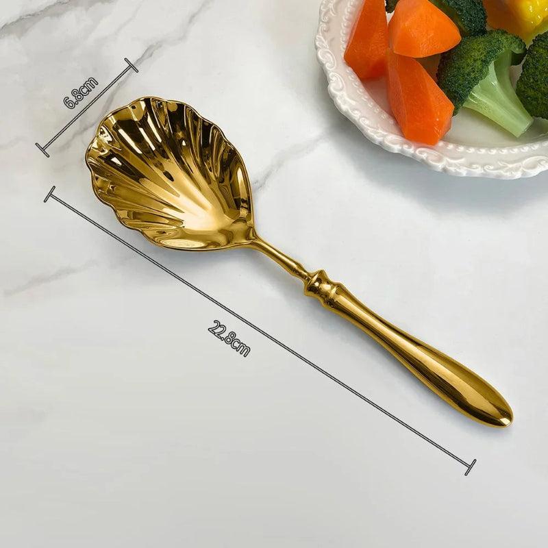 A product image of a single gold serving spoon with a scalloped, shell-shaped head, labeled with its dimensions.