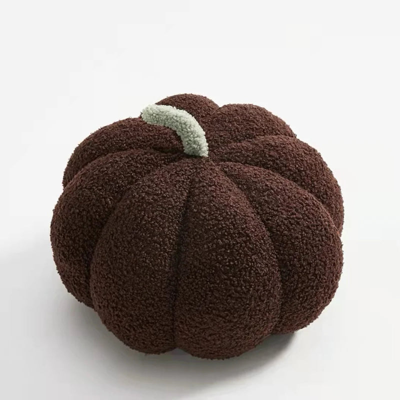 A fuzzy, dark brown pumpkin-shaped pillow with a light green stem.