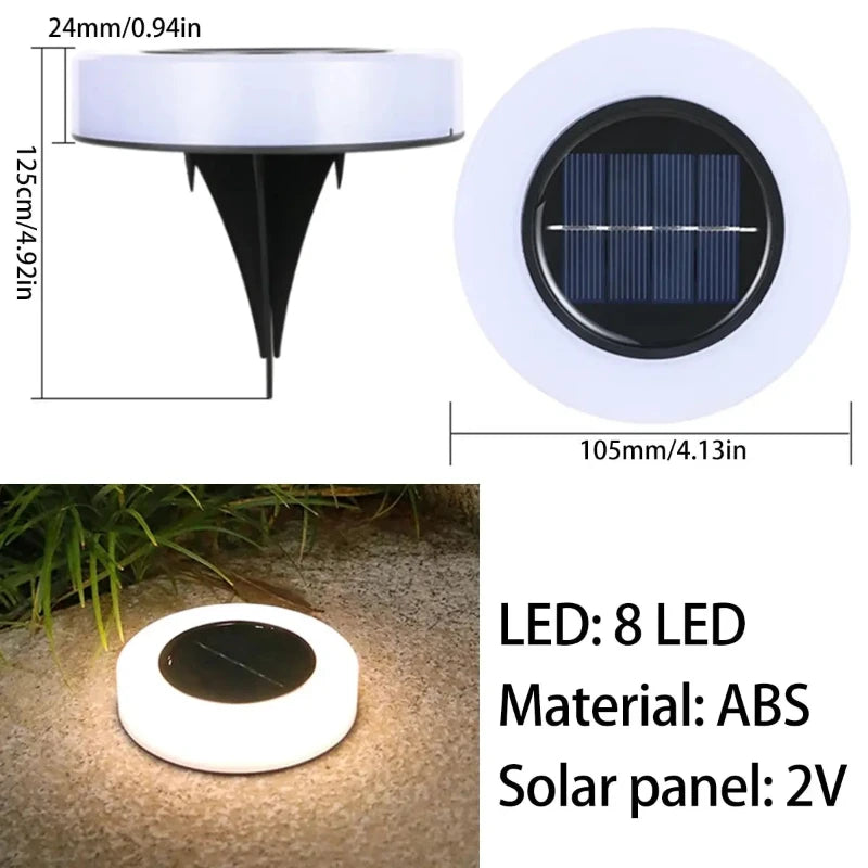 A composite image shows diagrams with dimensions and specifications of a round, white solar pathway light with a dark circular solar panel in the center and a black ground stake. The diagrams indicate a diameter of 105mm/4.13 inches and a height of the light head as 24mm/0.94 inches, while the total height including the stake is 125cm/4.92 inches. Text specifies 8 LEDs, ABS material, and a 2V solar panel. An example shows the light emitting a bright white glow when placed on the ground.