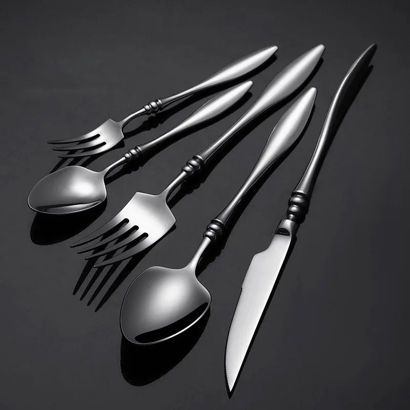 A set of six dark silver utensils on a black background.