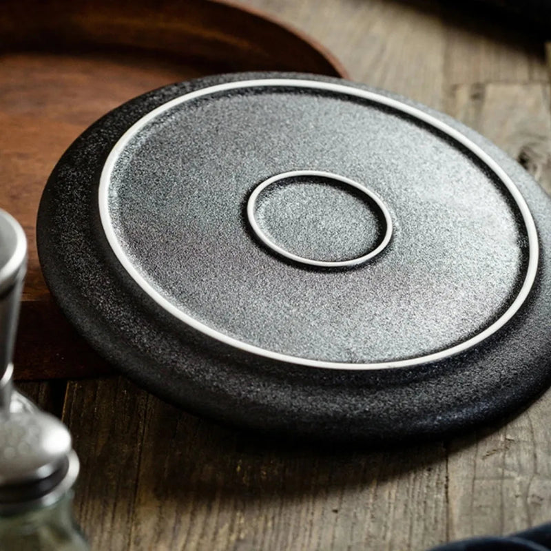 The bottom of a black speckled plate with a white rim, showing its raised base.