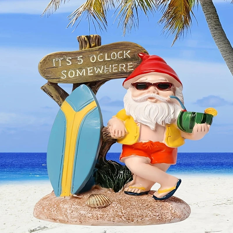 A whimsical garden gnome figurine with a long white beard and sunglasses, wearing a red pointed hat, a yellow open shirt, and red shorts with blue and yellow sandals, stands on a sandy base with seashells. He holds a green coconut drink with a straw and a slice of orange in one hand. Behind him is a weathered wooden sign that reads "IT'S 5 O'CLOCK SOMEWHERE," leaning against a blue and yellow surfboard. The background shows a sunny beach scene with blue water, a clear sky, and palm trees.