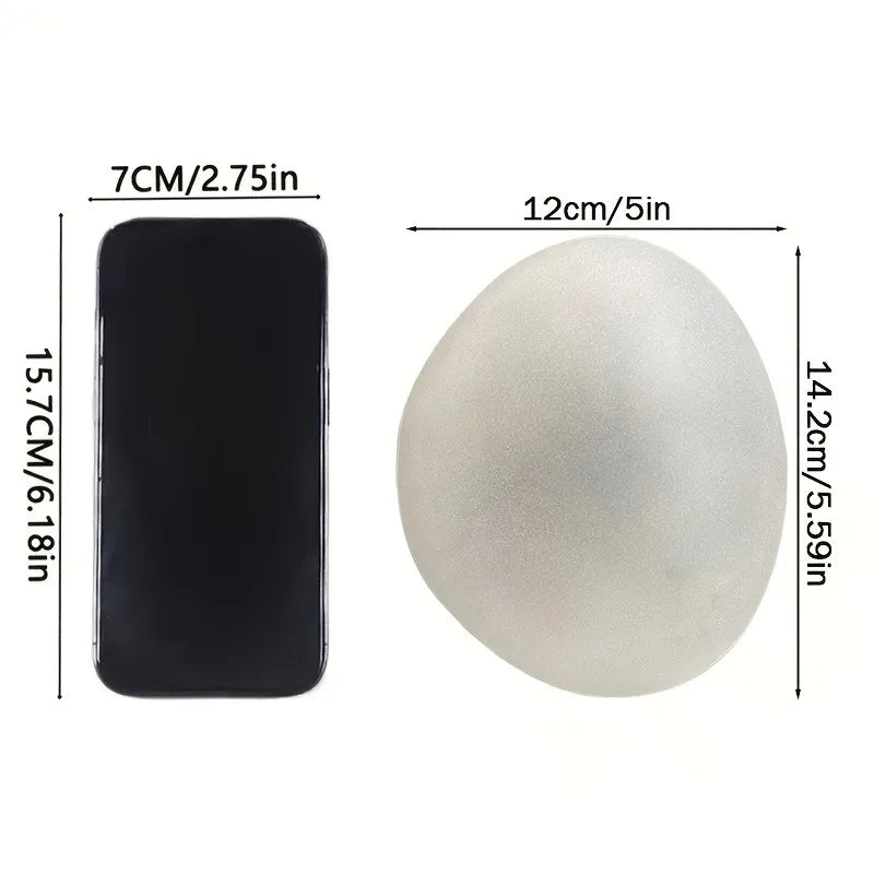 A side-by-side comparison of a black smartphone and a white, egg-shaped light, showing their dimensions in centimeters and inches.
