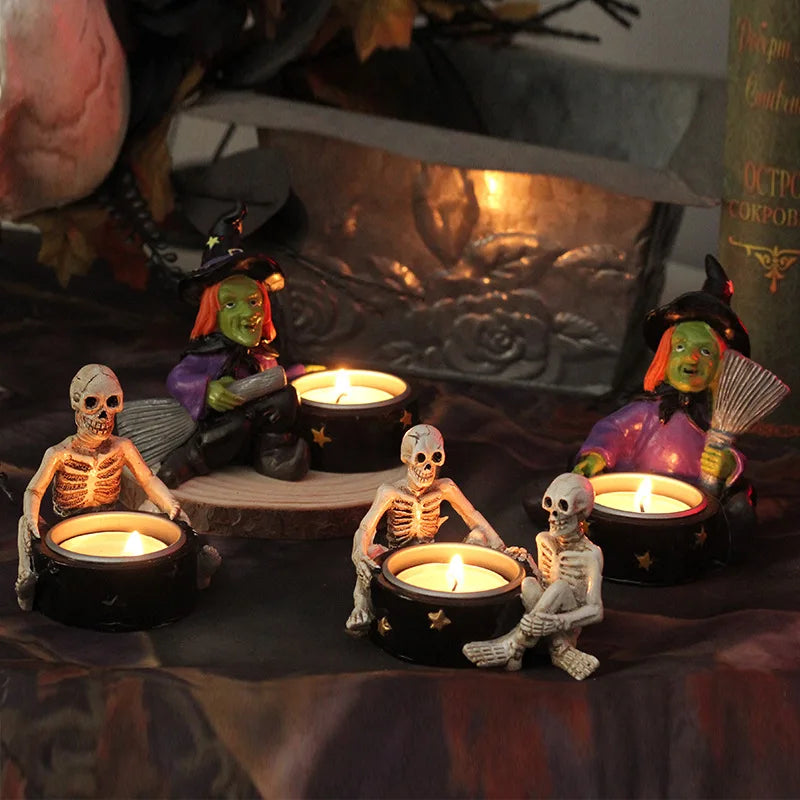 Three skeleton figurines and two witch figurines with lit candles, set up for a Halloween display.