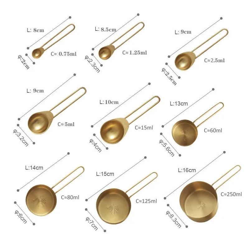 A close-up of a set of nine individual brass measuring spoons and cups, each labeled with its length and capacity.