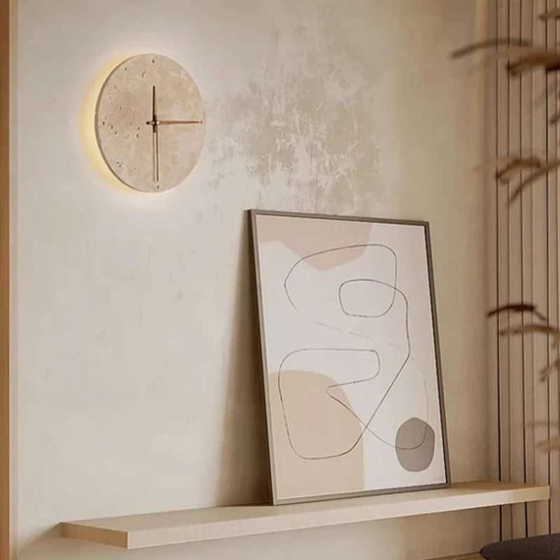 A round wall clock with a light-colored, textured face and simple red hands is mounted on a light beige wall.