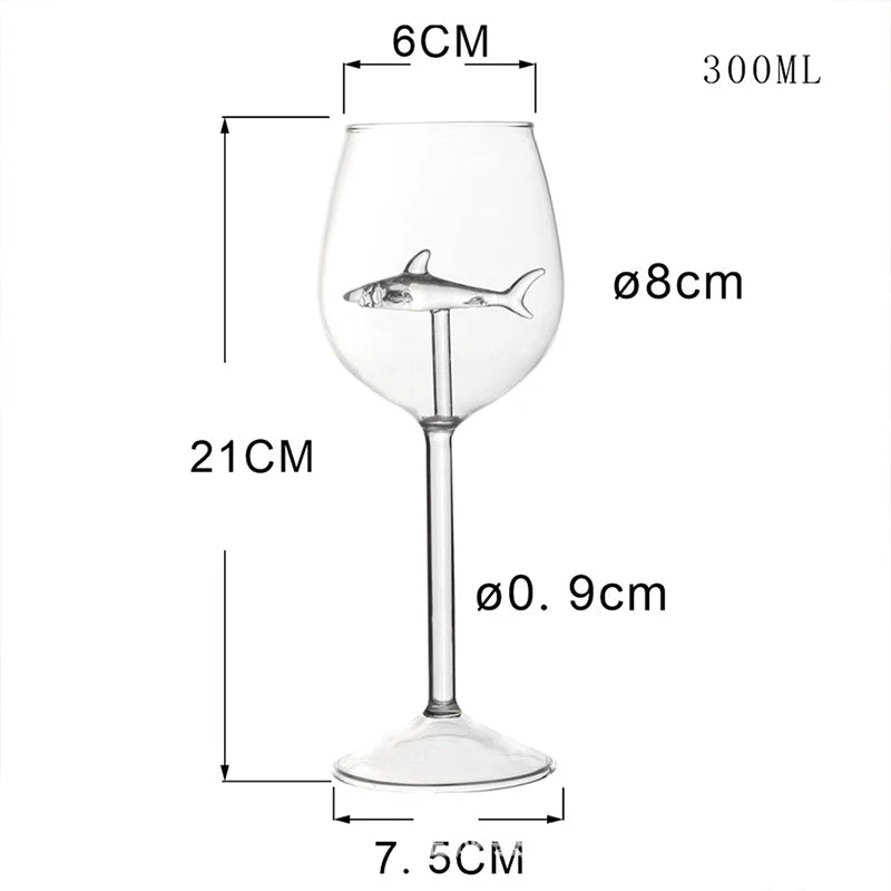A product image of an empty wine glass with a shark figurine inside, labeled with its dimensions.