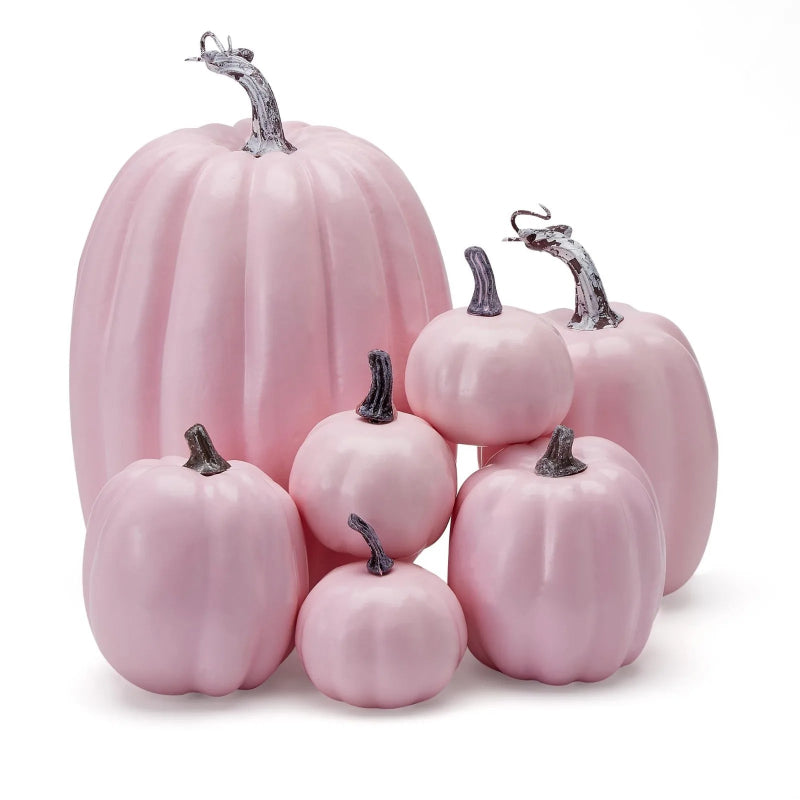 A cluster of light pink decorative pumpkins of various sizes with grey stems.