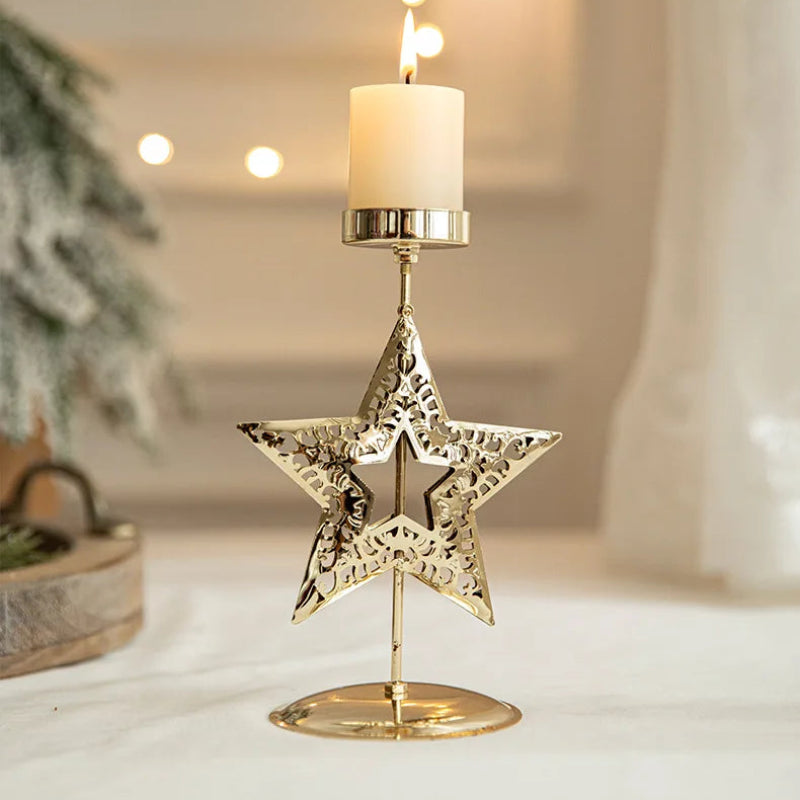Lit candle in a gold star-shaped candle holder on a white surface.