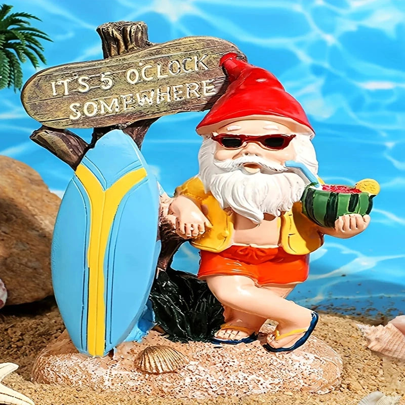 A whimsical garden gnome figurine with a long white beard and sunglasses, wearing a red pointed hat, a yellow open shirt, and red shorts with blue sandals, stands on a sandy base with seashells. He holds a green coconut drink garnished with fruit in one hand and a straw to his mouth. Behind him is a weathered wooden sign that reads "IT'S 5 O'CLOCK SOMEWHERE," leaning against a blue and yellow surfboard. The background features a bright blue, slightly blurred image suggesting water and a sunny day. A hint of