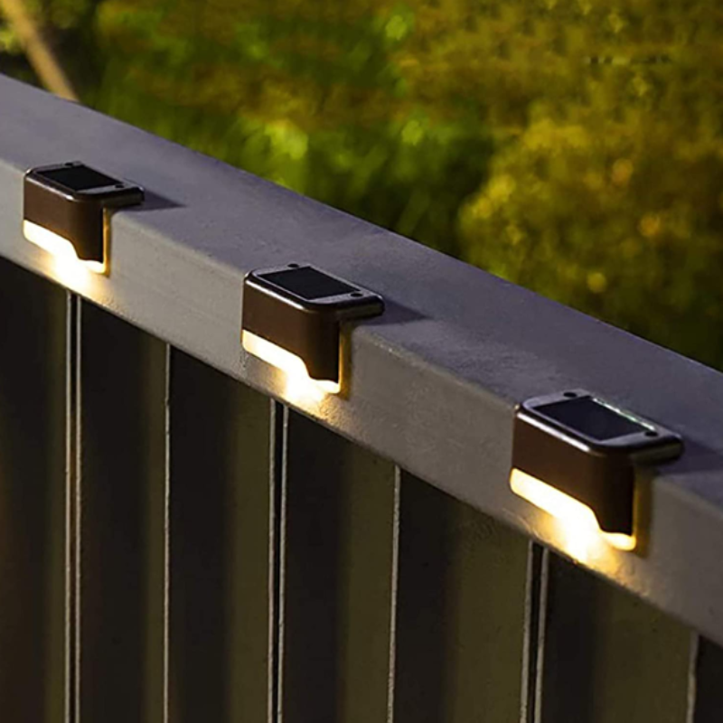 Three small, dark, rectangular lights are mounted on a gray railing, casting a warm white downward glow.