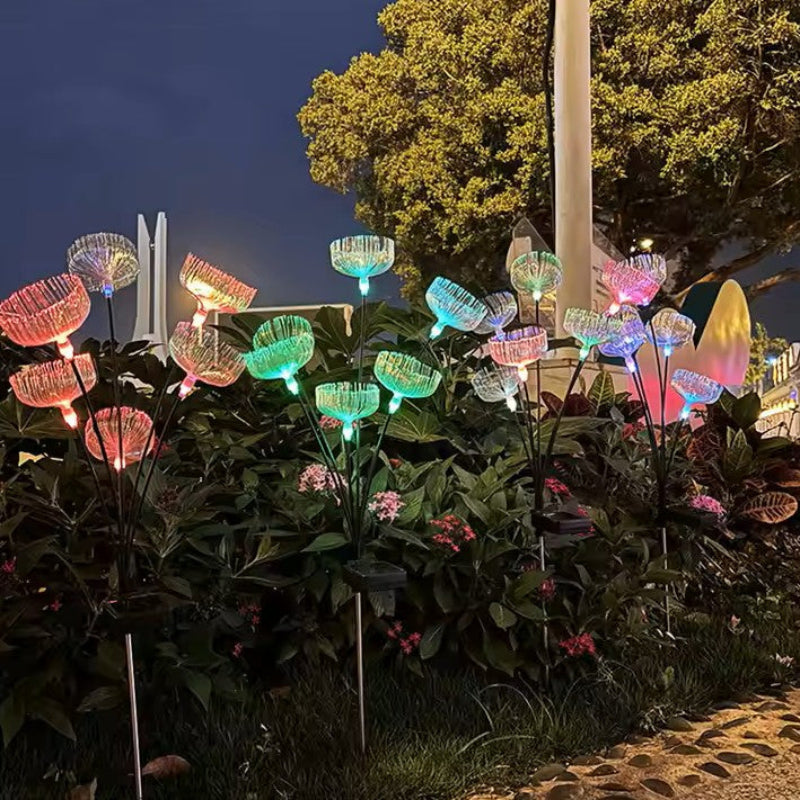 Colorful, jellyfish-shaped solar garden lights illuminate a garden at dusk.