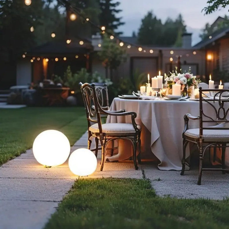 Outdoor dining setup with string lights and decorative candles in a backyard.