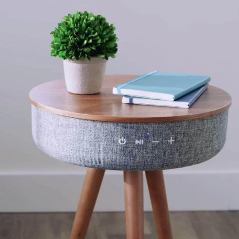 Round side table with wooden top and gray textured base, featuring a plant and books on top.