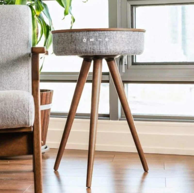 Wooden side table with a textured top in a room with a chair and window.