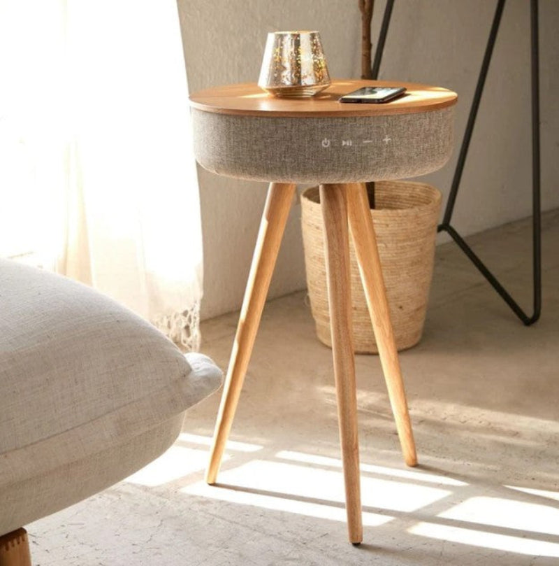 Modern side table with wooden legs and a round top in a living room setting.