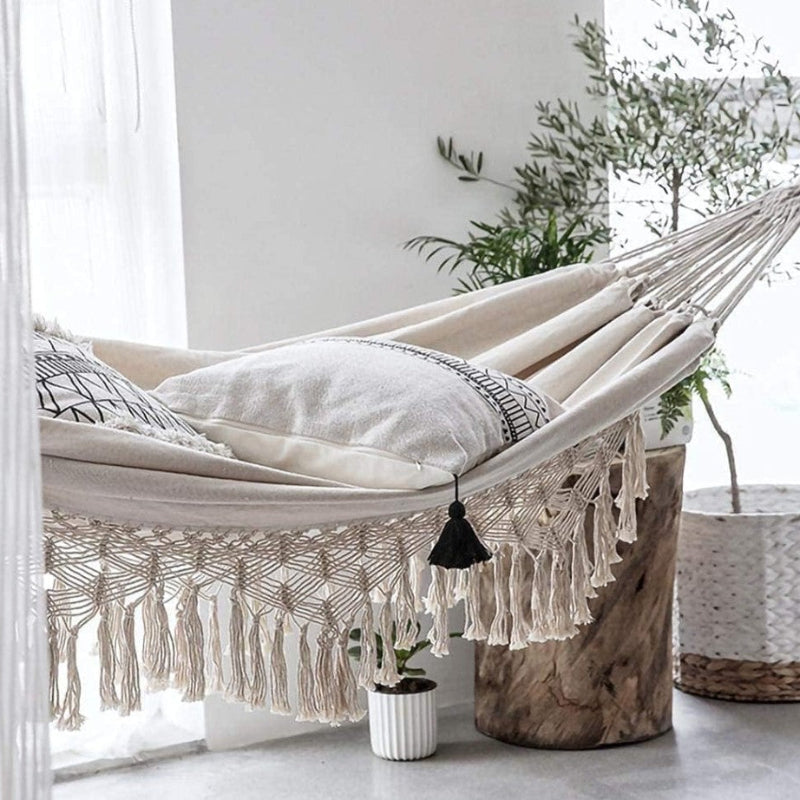 Beige hammock with tassels in a bright room with plants
