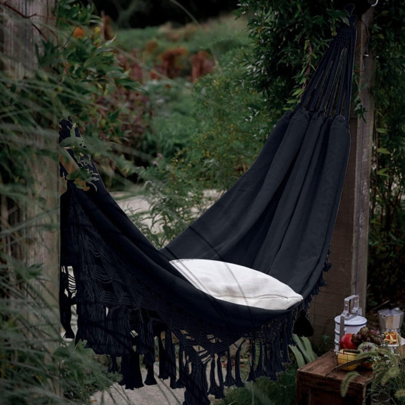 Black hammock with white pillow in a garden setting