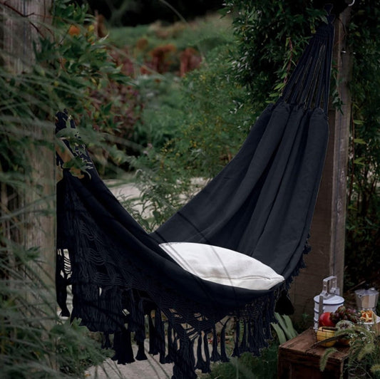 Black hammock with white pillow in a garden setting