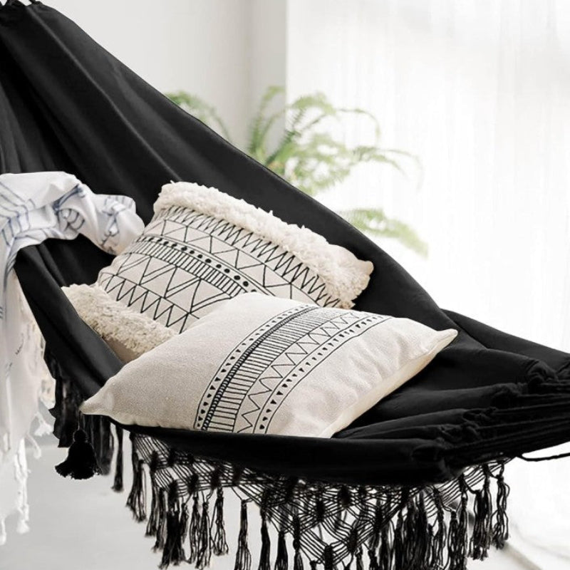Black hammock with white pillows and a blanket in a bright room