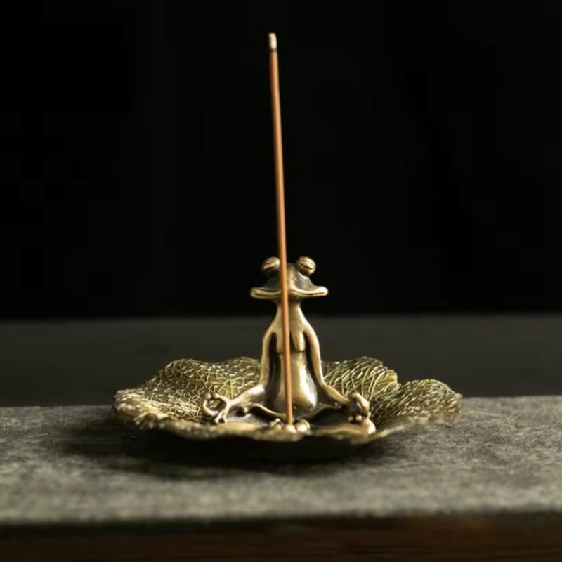 Brass incense holder with a single incense stick on a dark background
