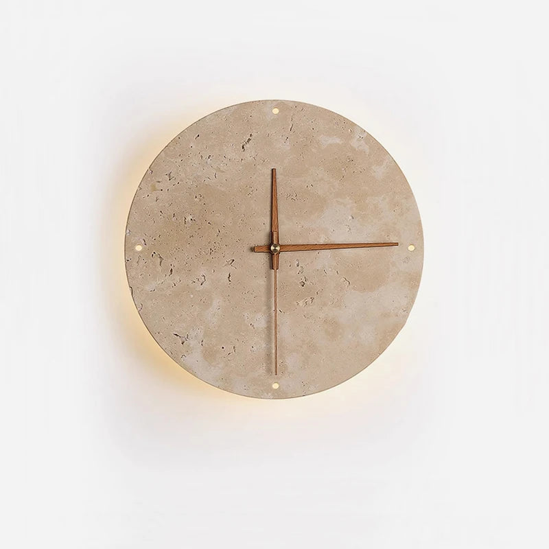 A round wall clock with a light-colored, textured stone face and simple brown hands is mounted on a white wall. The clock is softly backlit, creating a subtle warm glow around its edge.