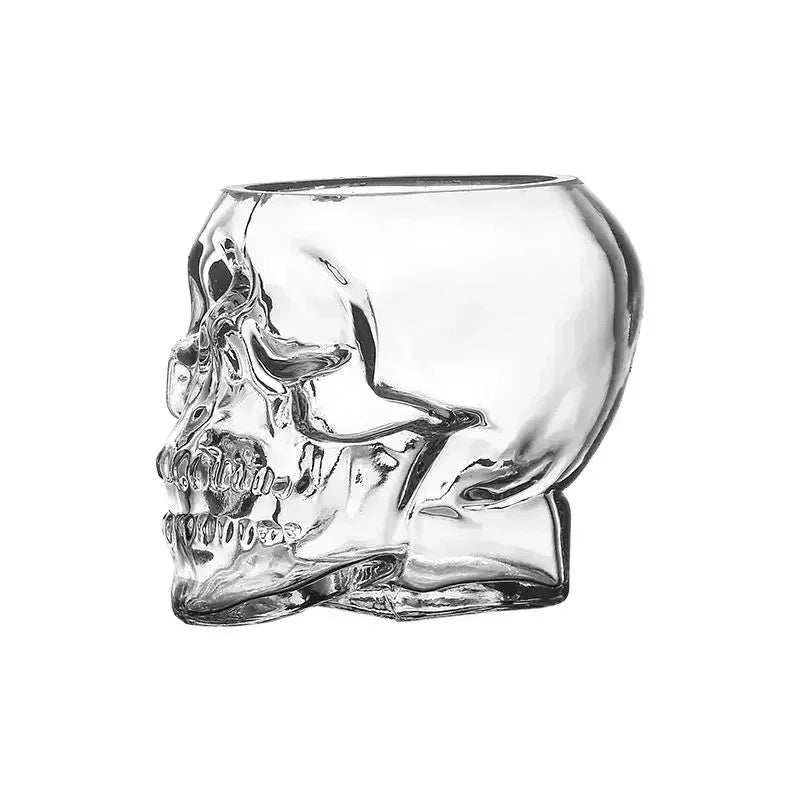 A clear glass cup shaped like a human skull, viewed from the side, isolated on a white background.