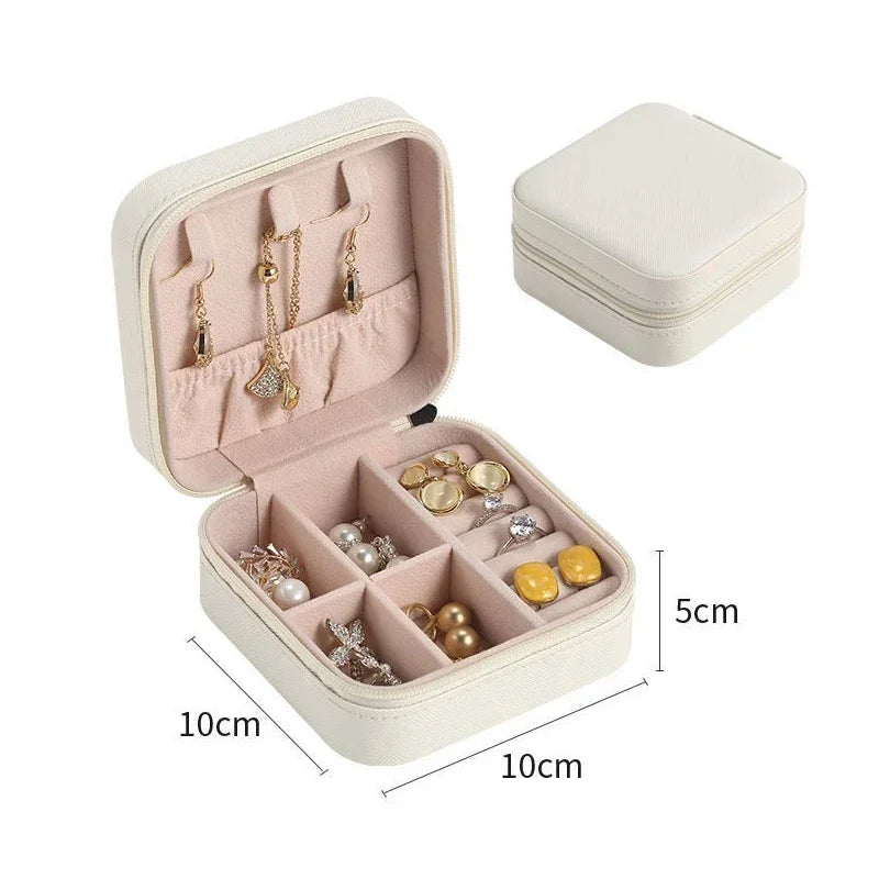 An open white square jewelry box filled with various earrings and rings, with a closed matching box in the background, showing dimensions of 10cm x 10cm x 5cm.