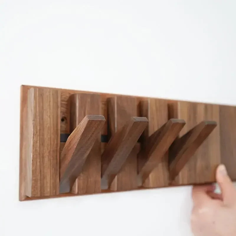 Wooden wall-mounted coat rack with a hand holding it on a white background