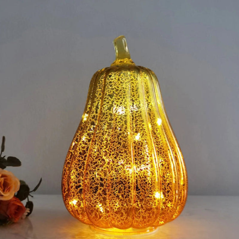 A tall, glowing, pear-shaped pumpkin decoration in a shiny, gold-colored finish with internal lights.