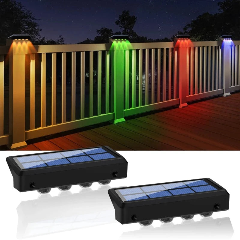 Four solar-powered post lights with color-changing LEDs illuminate a white wooden railing with orange, green, red, and blue beams at night. Below, two individual solar fence lights with solar panels and multiple small LED bulbs are shown against a white background.