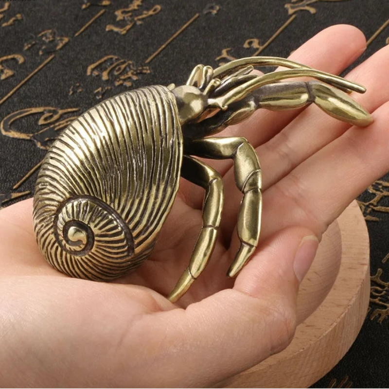 Bronze crab sculpture held in a hand against a decorative background