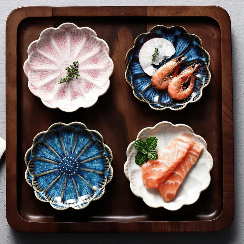 Four flower-shaped ceramic dishes on a wooden tray, two holding shrimp and salmon, and two empty.