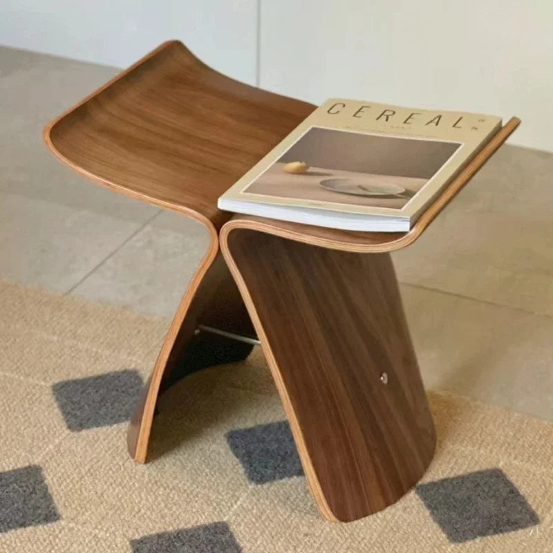 A brown, bent plywood Butterfly Stool with a magazine on top.