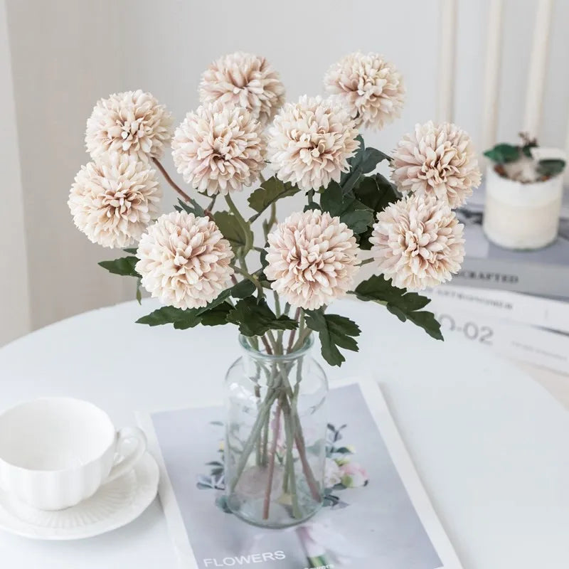 Faux pink flowers in a clear vase on a white table.