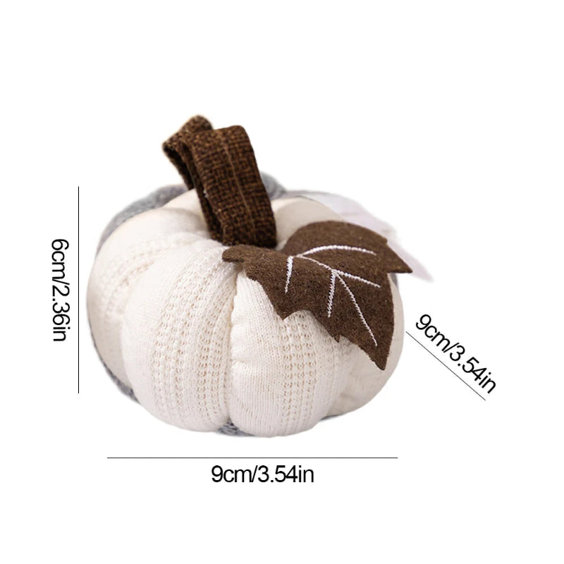 A white knitted pumpkin with a brown stem and a brown leaf is shown with dimensions of 9cm (3.54in) in width and depth, and 6cm (2.36in) in height, on a white background.