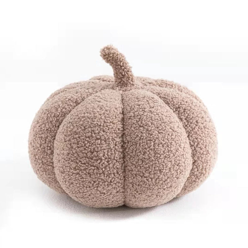 A light brown, fuzzy, pumpkin-shaped pillow with a short, curved stem.