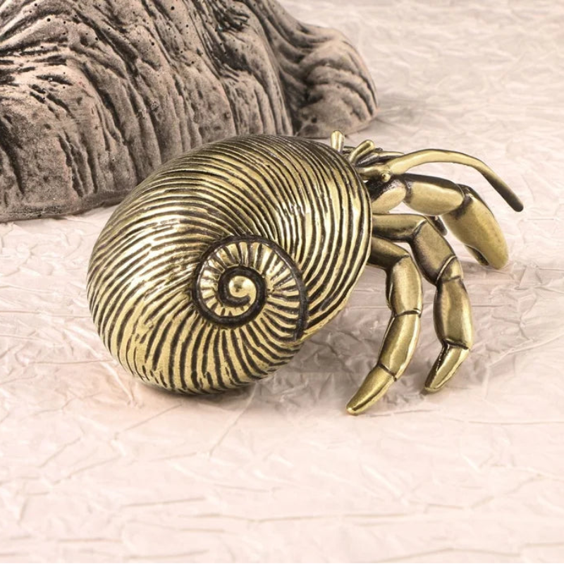 Bronze crab with shell on a textured beige surface