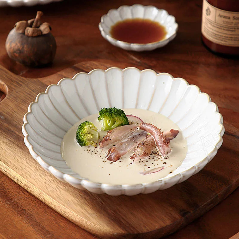 A large scalloped-edge bowl with food in it, next to a small dish with sauce.