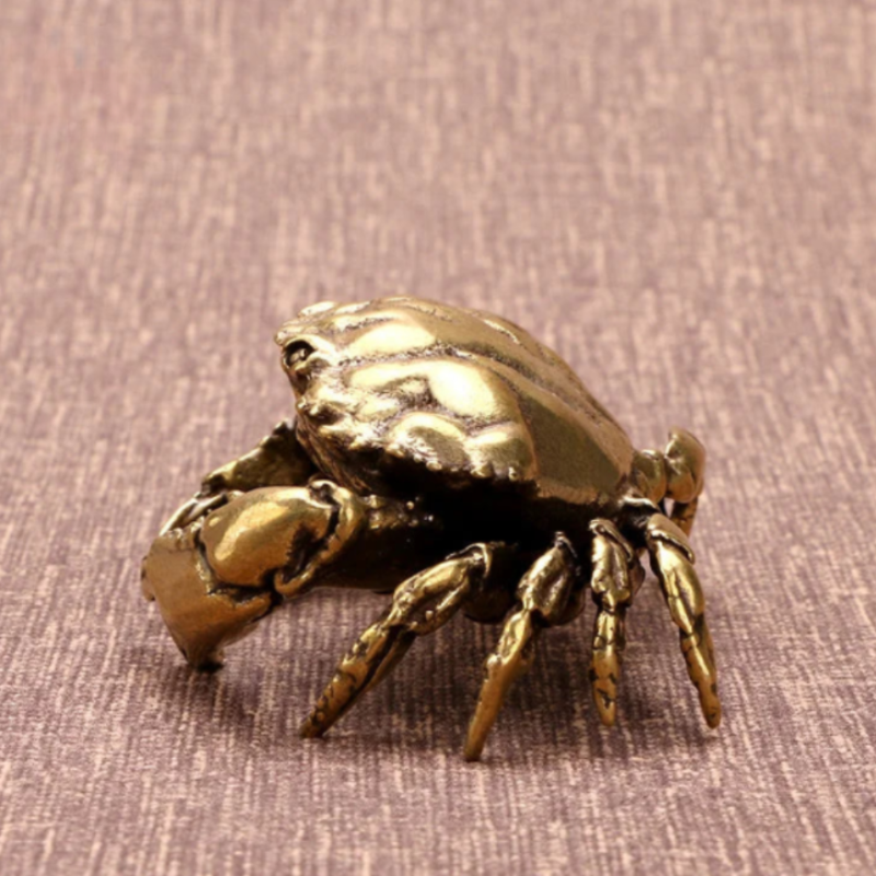Bronze crab figurine on a textured brown surface